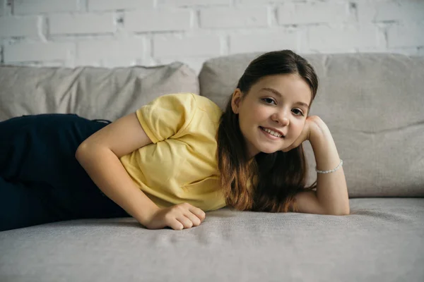 Брюнетка дівчина посміхається на камеру, відпочиваючи на дивані у вітальні — стокове фото