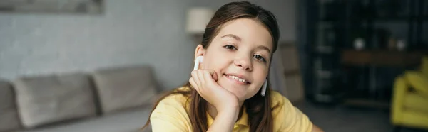 Portrait of pleased girl in wireless earphones listening music at home, banner — Stock Photo