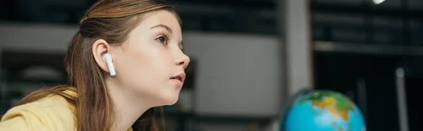 Vista lateral de la chica de ensueño en auriculares inalámbricos escuchando audiolibro y mirando hacia otro lado, banner - foto de stock