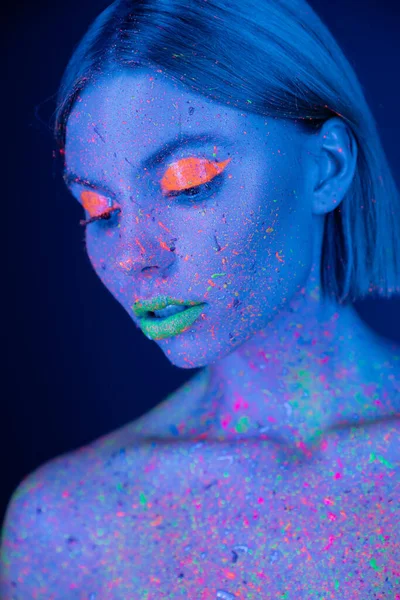 Retrato de mulher em maquiagem de néon brilhante e salpicos de tinta brilhante isolados em azul escuro — Fotografia de Stock