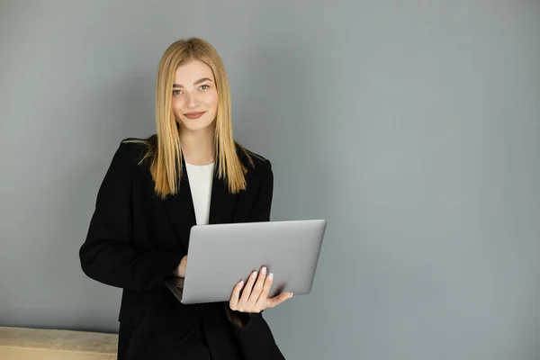 Smiling blonde coach holding laptop and looking at camera at home — Stock Photo