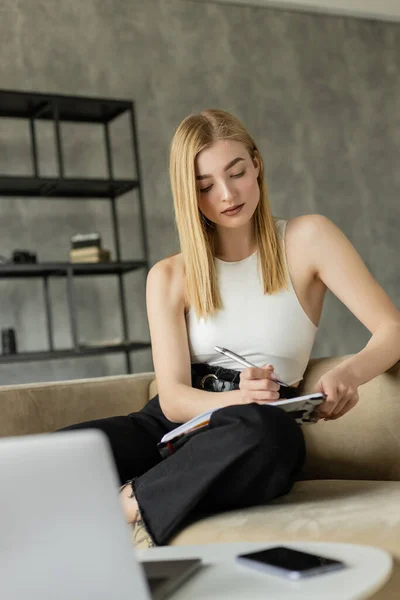 Mulher bonita olhando para notebook perto de dispositivos borrados durante o e-learning em casa — Fotografia de Stock