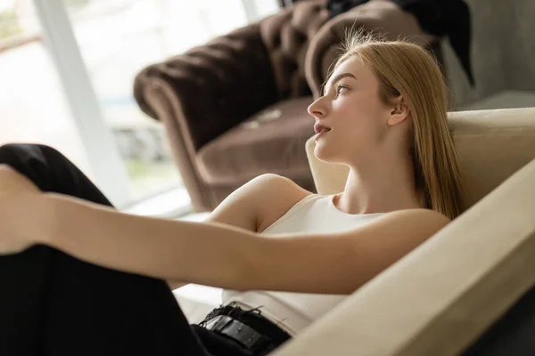 Young woman in jeans and top resting on sofa at home — Stock Photo