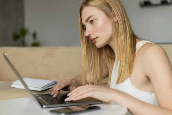 Konzentrierter Trainer mit Laptop neben Handy am heimischen Tisch — Stockfoto