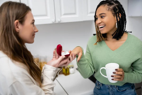 Young lesbian woman making proposal to happy african american girlfriend on valentines day — Stock Photo