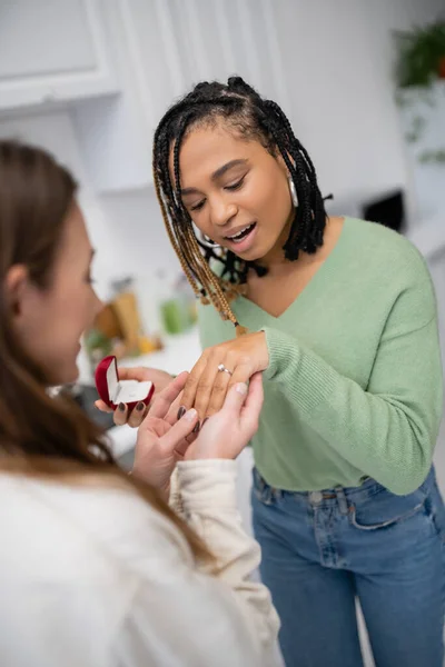 Lesbian woman making proposal to stunned african american girlfriend on valentines day — Stock Photo