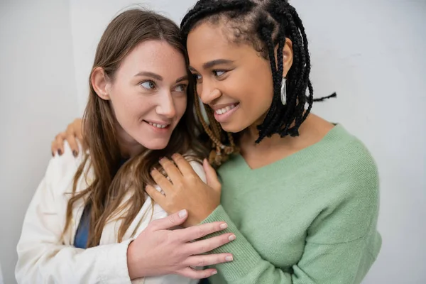 Щасливі міжрасові і лесбіянки посміхаються, обнімаючи один одного — стокове фото
