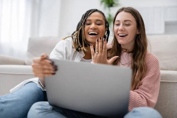 Lesbian african american woman showing engagement ring near amazed girlfriend during video call — Stock Photo