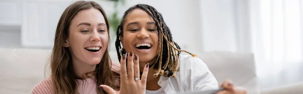 Lesbian african american woman showing engagement ring near amazed girlfriend, banner — Stock Photo