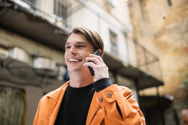 Cheerful young man talking on smartphone in outdoor cafe — Stock Photo