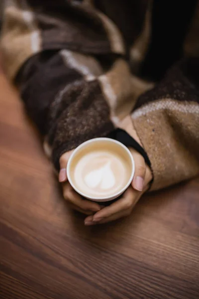 Vista dall'alto della donna in coperta che tiene il cappuccino nel caffè all'aperto — Foto stock