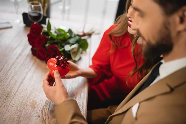 Бородатий чоловік дарує подарунок у формі серця з луком щасливій дівчині в день валентинки — стокове фото