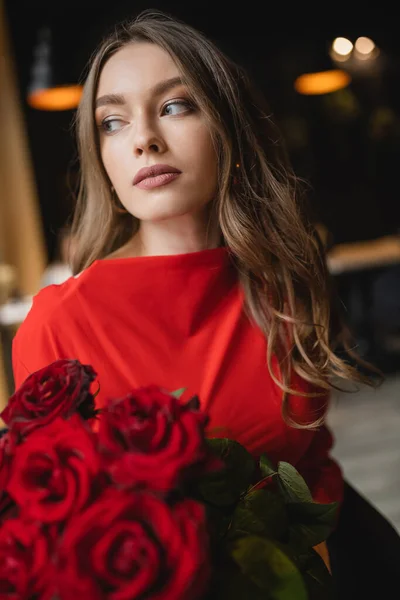 Bonita mujer joven sosteniendo ramo de rosas rojas en el día de San Valentín - foto de stock