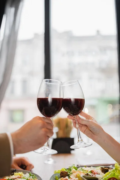 Visão parcial do casal copos clinking com vinho tinto durante a celebração no dia dos namorados — Fotografia de Stock