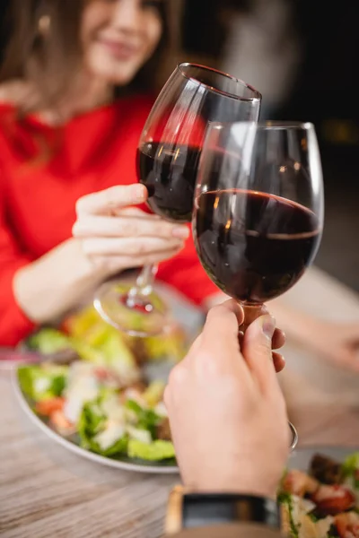 Cropped view of couple clinking glasses with red wine during celebration on valentines day — Stock Photo