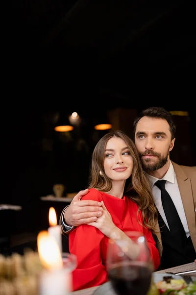 Bearded man hugging young woman in red dress on valentines day — Stock Photo