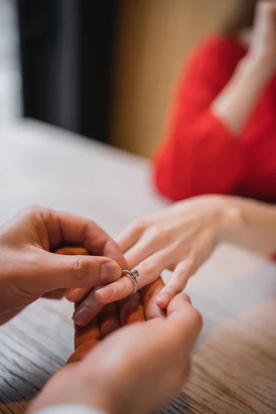 Vista recortada del hombre que lleva anillo de compromiso en el dedo de la novia en el día de San Valentín - foto de stock