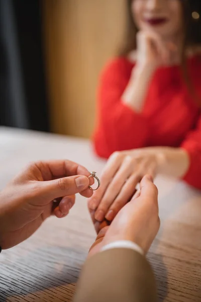 Vista recortada del hombre sosteniendo anillo de compromiso y la mano de la novia en el día de San Valentín - foto de stock