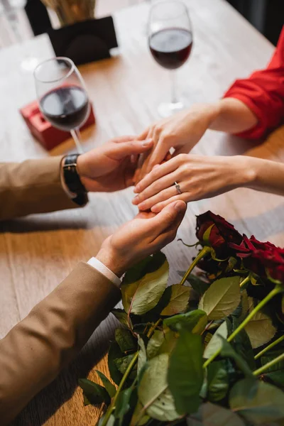 Vista cortada de mulher com anel de noivado no dedo de mãos dadas com namorado no dia dos namorados — Fotografia de Stock