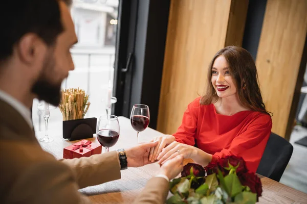 Mujer feliz con anillo de compromiso en el dedo cogido de la mano con el hombre en el día de San Valentín - foto de stock