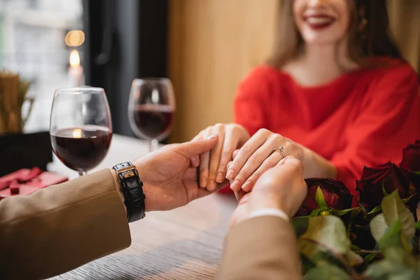 Vista cortada de mulher feliz com anel de noivado no dedo de mãos dadas com o homem no dia dos namorados — Fotografia de Stock