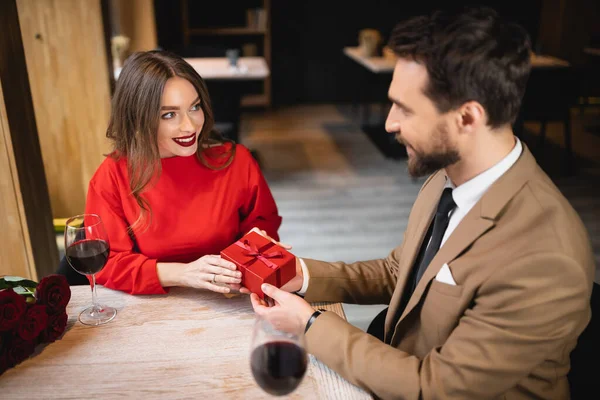 High angle view of bearded man holding wrapped present near happy woman on valentines day — Stock Photo
