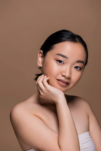 Portrait of smiling asian model looking at camera isolated on brown — Stock Photo