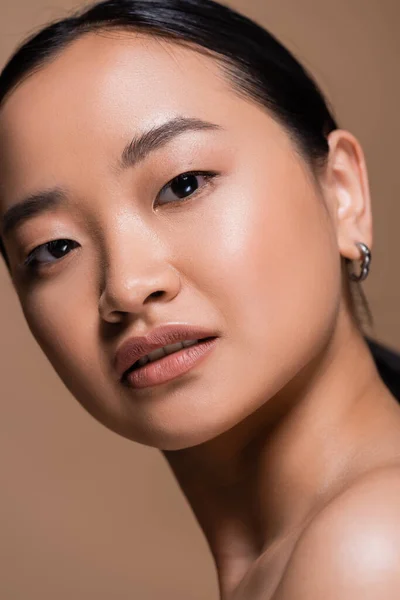 Close up view of young asian woman with naked shoulder looking at camera isolated on brown — Foto stock