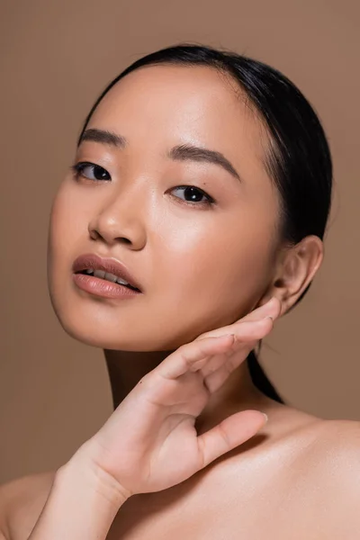 Portrait of young asian woman touching face isolated on brown — Foto stock