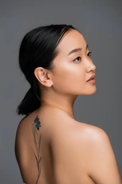 Жінка з татуюванням на спині виглядала ізольованою на сірому — стокове фото