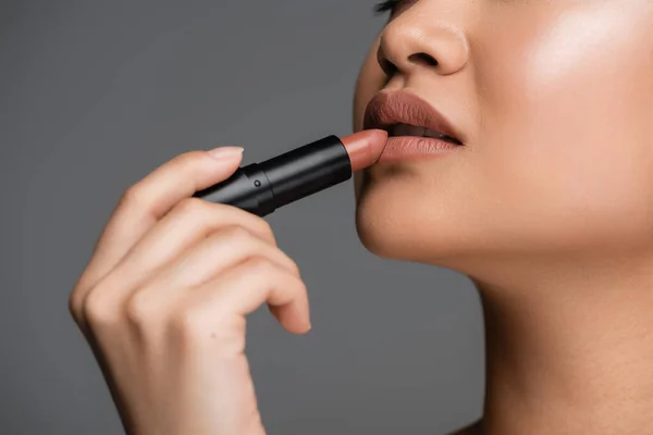 Cropped view of young woman applying lipstick isolated on grey — Stockfoto