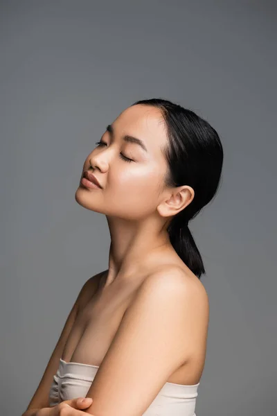 Charming asian woman with closed eyes and perfect skin posing isolated on grey — Stock Photo