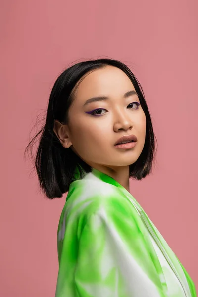 Portrait of young asian woman with makeup looking at camera isolated on pink — Foto stock