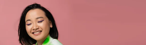 Portrait of happy asian woman with makeup and brunette hair isolated on pink, banner — Foto stock