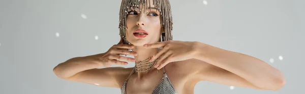 Trendy young model in jewelry headwear posing and looking away on grey background with light, banner — Stock Photo