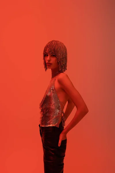 Stylish young woman in jewelry headwear posing and looking at camera isolated on red — Stock Photo