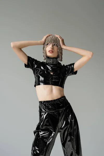 Young woman in jewelry headwear and latex clothes posing isolated on grey — Photo de stock