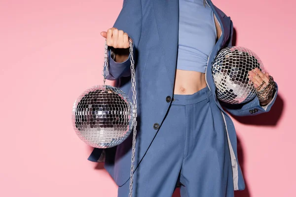 Cropped view of stylish woman in suit holding disco balls on pink background — Fotografia de Stock