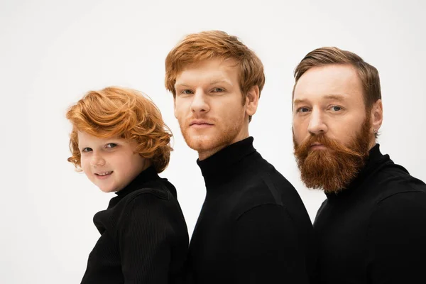 Red haired men and smiling boy in black turtlenecks looking at camera isolated on grey — Stockfoto
