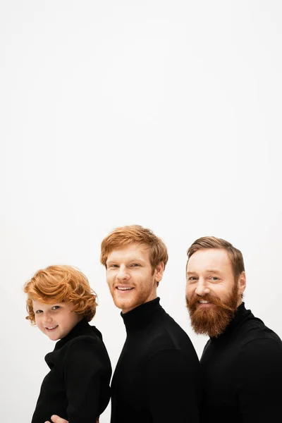 Joyful bearded men and redhead boy in black turtlenecks smiling at camera isolated on grey — Stock Photo