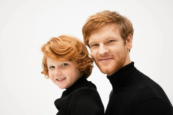 Family portrait of redhead dad and son in black sweaters smiling at camera isolated on grey — Stock Photo