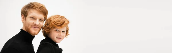 Family portrait of young man smiling at camera with redhead son isolated on grey, banner — Stock Photo