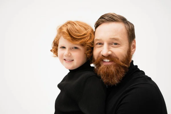 Joyful bearded man with redhead grandson smiling at camera isolated on grey — Stockfoto