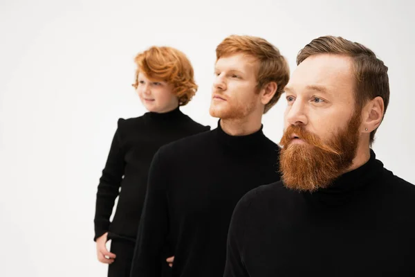 Adult bearded men and redhead boy in black turtlenecks looking away isolated on grey — Stock Photo