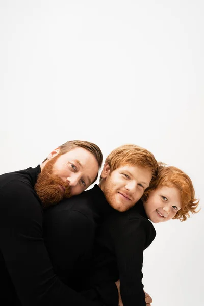 Family portrait of redhead bearded men and boy in black sweaters looking at camera isolated on grey — Stock Photo