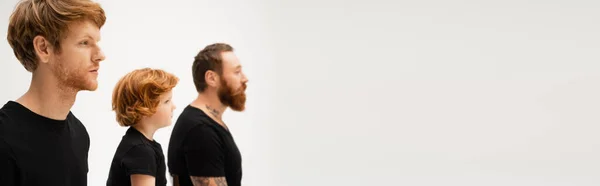 Side view of bearded men and red haired kid in black t-shirts isolated on grey, banner — Stock Photo