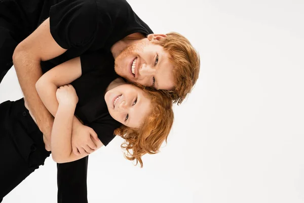 Happy man embracing redhead son while having fun and looking at camera isolated on grey — Stock Photo