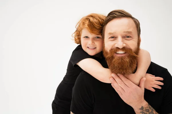 Cheerful kid hugging happy bearded grandfather and looking at camera isolated on grey — Stock Photo