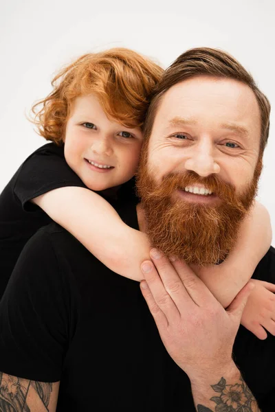 Pleased redhead child hugging happy bearded granddad while looking at camera isolated on grey — Stock Photo