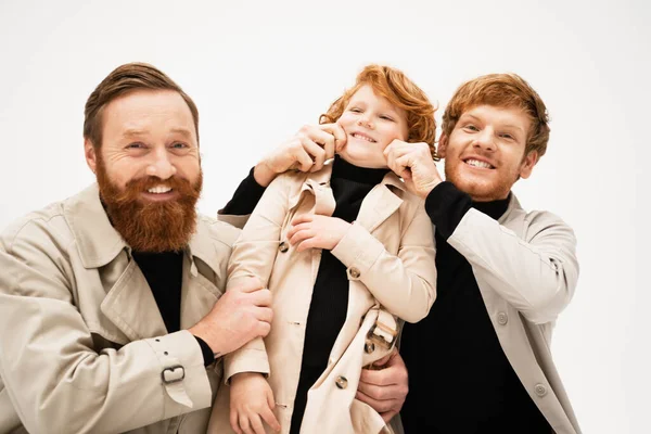 Happy bearded man looking at camera near redhead son and grandson having fun isolated on grey — Stock Photo